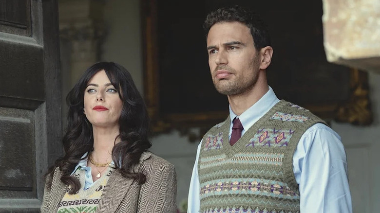 Kaya Scodelario as Susie in wool blazer and sweater next to Theo James as Eddie in tie and sweater vest in "The Gentlemen."