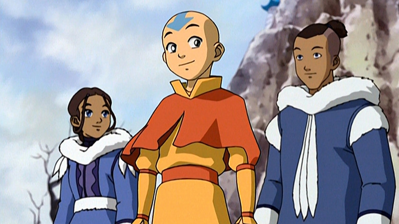 Aang (Zach Tyler Eisen) stands smiling in front of Katara (Mae Whitman) and Sokka (Jack De Sena) in Avatar: The Last Airbender
