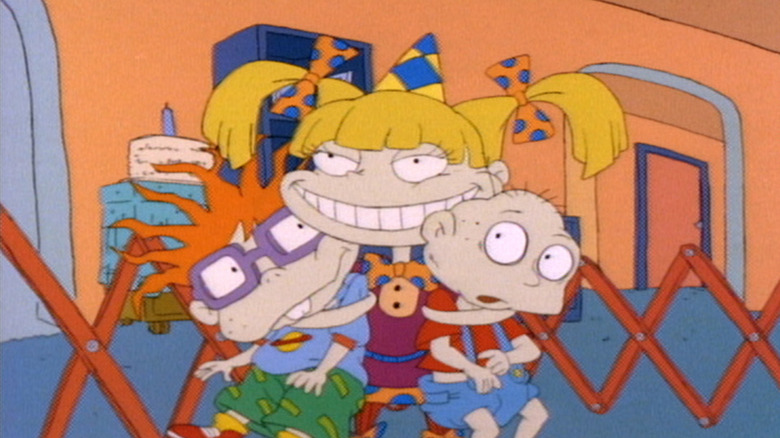 Angelica Pickles (Cheryl Chase) grins while holding Chucky Finster (Christine Cavanaugh) and Tommy Pickles (E.G. Daily) in Rugrats (1991)