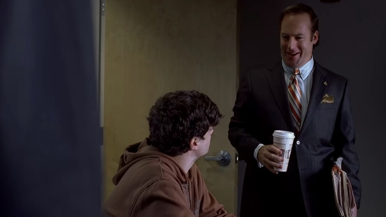 Saul Goodman (Bob Odenkirk) greets a seated Badger Mayhew (Matt Jones) in Breaking Bad