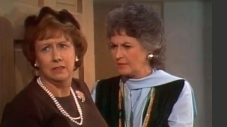 Edith Bunker (Jean Stapleton) and Maude Findlay (Bea Arthur) look skeptically in a doorway in All in the Family