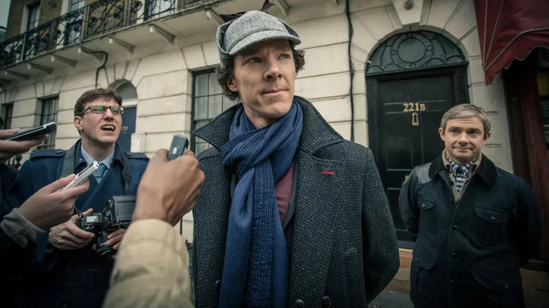 Benedict Cumberbatch's Sherlock Holmes facing reporters while Martin Freeman's John Watson watches on Sherlock