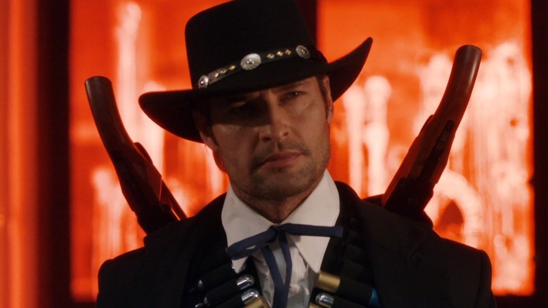 Josh Holloway as the Black Rider, standing in front of paint in Community.