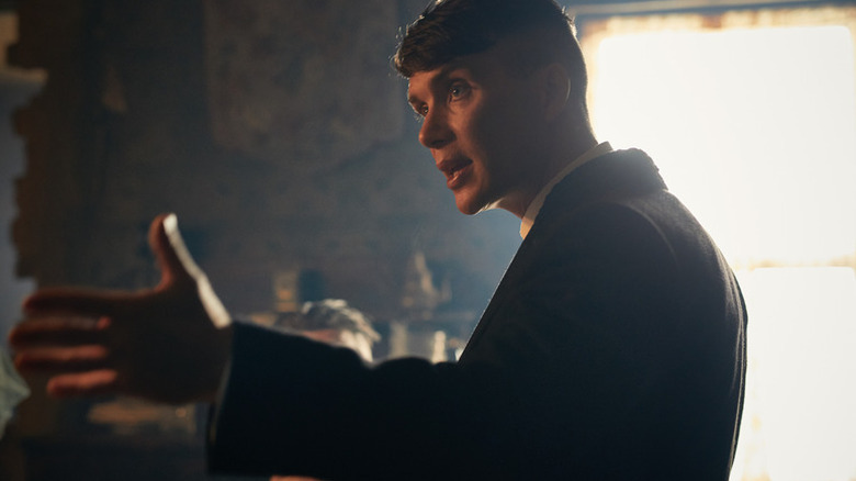 Tommy Shelby (Cillian Murphy) speaks animatedly while holding out a hand in Peaky Blinders