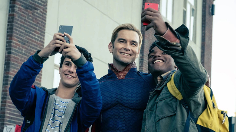 Homelander (Antony Starr) smiles as he takes selfies with fans in The Boys