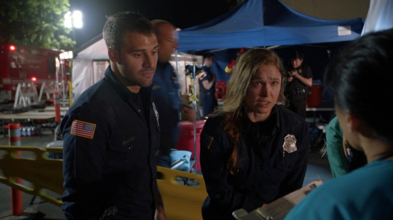 Lena standing next to Eddie amongst medical tents
