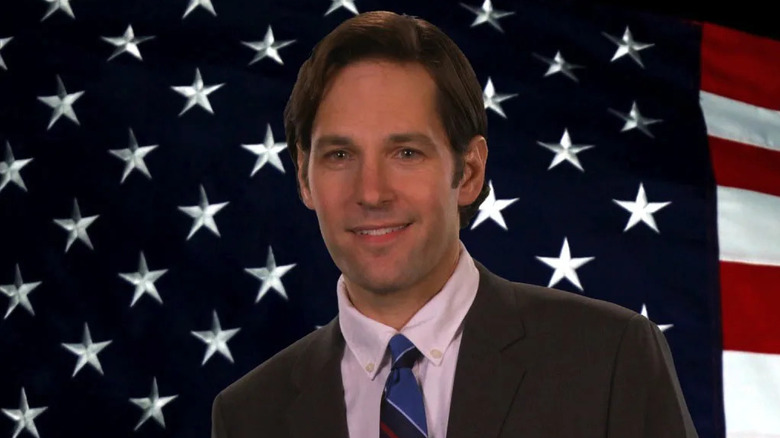 Paul Rudd as Bobby Newport smiling in front of the American flag in Parks & Recreation
