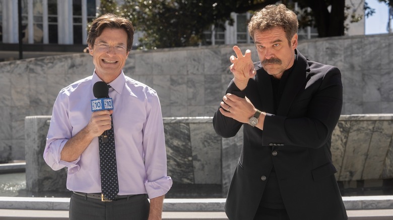 Jason Bateman as Clark holding news microphone next to David Harbour as Floyd doing sign language in DTF St. Louis