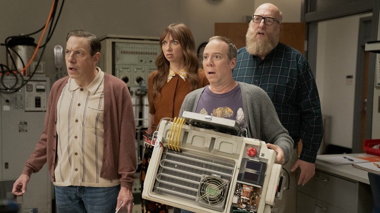 John Ross Bowie as Kripke, Lauren Lapkus as Denise, Brian Posehn as Bert, and Kevin Sussman as Stuart, holding large machine, in Stuart Fails to Save the Universe