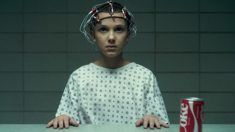 Eleven sits with electrodes strapped to head
