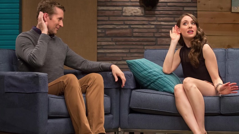Scott Aukerman sitting across from Alison Brie on the set of Comedy Bang Bang