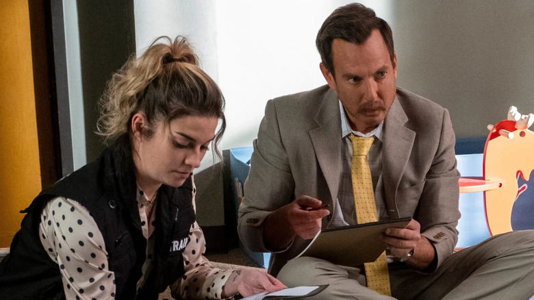 Annie Murphy and Will Arnett taking notes on the floor in Murderville