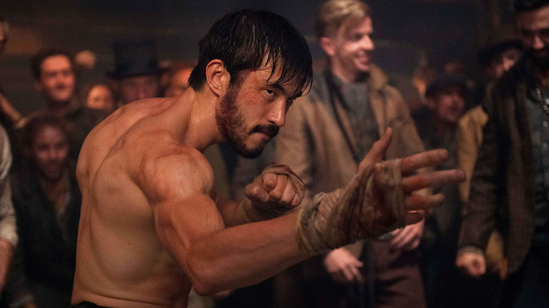A topless and muscular Ah Sahm (Andrew Koji) strikes a fighting pose in Warrior