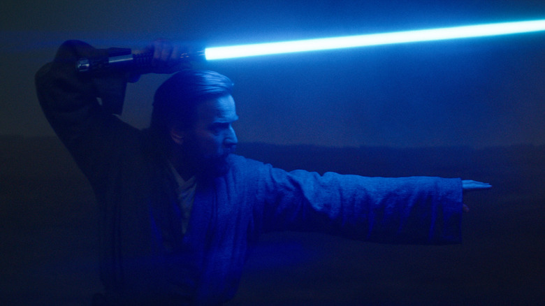 Ewan McGregor as Obi-Wan wielding a blue lightsaber and posing in Obi-Wan Kenobi