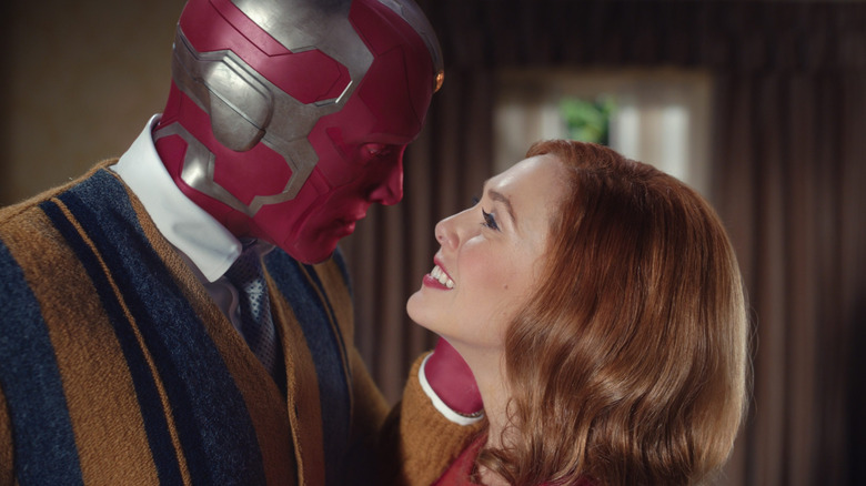 Paul Bettany as Vision in a sweater facing Elizabeth Olsen as Wanda smiling in WandaVision