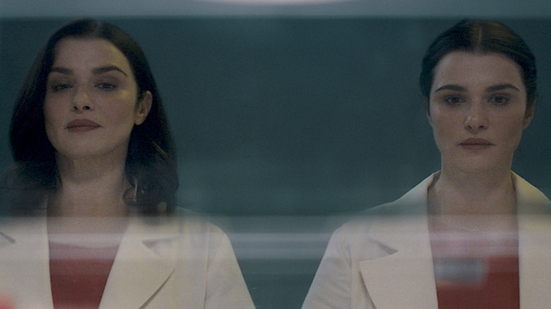 Rachel Weisz as twin sisters Elliot and Beverly wearing matching red tops and white doctor's coats in Dead Ringers