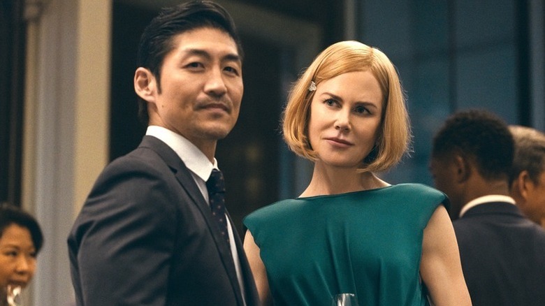 Brian Tee as Clarke standing next to Nicole Kidman as Margaret in dressy clothes in Expats