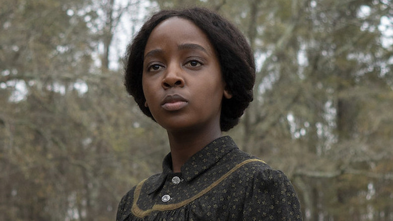 Thuso Mbedu as Cora standing outside in a dress in The Underground Railroad