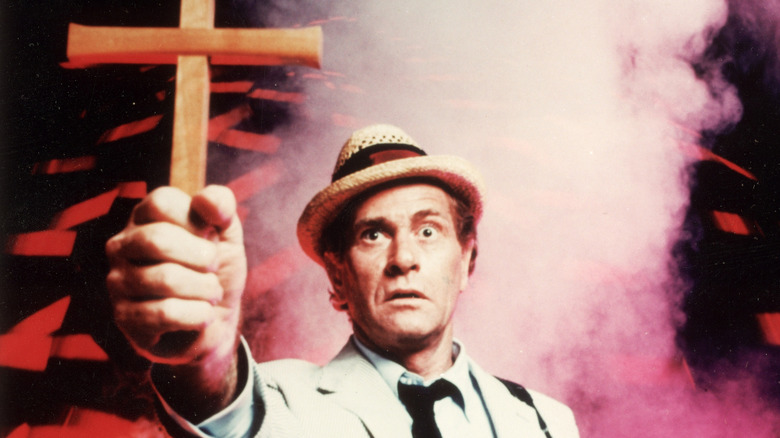 Carl Kolchak holding a crucifix and looking shocked
