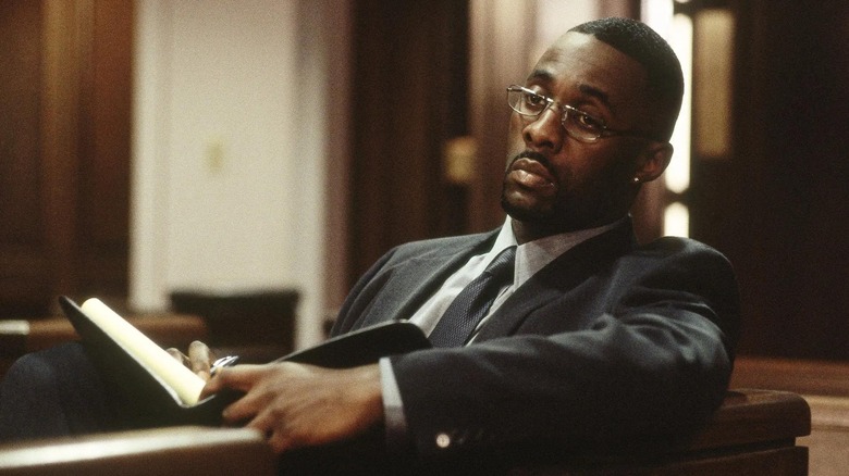 Stringer Bell (Idris Elba) sits with a ledger in a courtroom in The Wire