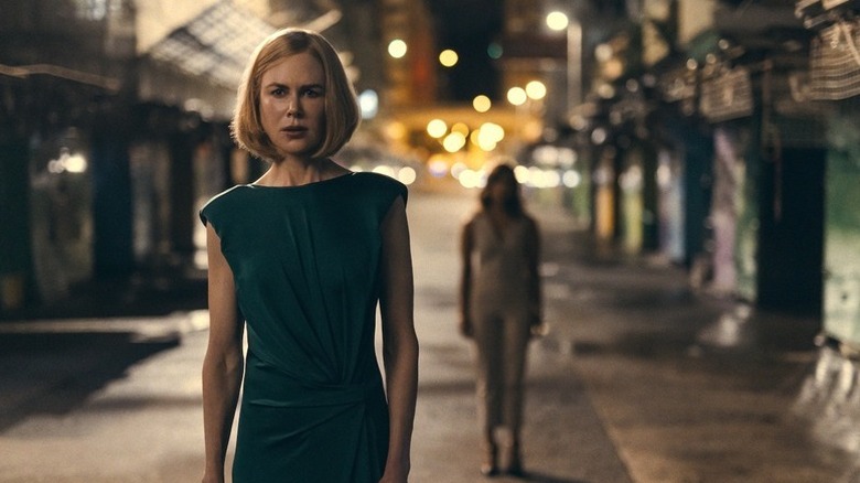 Nicole Kidman as Margaret standing in empty street with blurry figure behind her in Expats