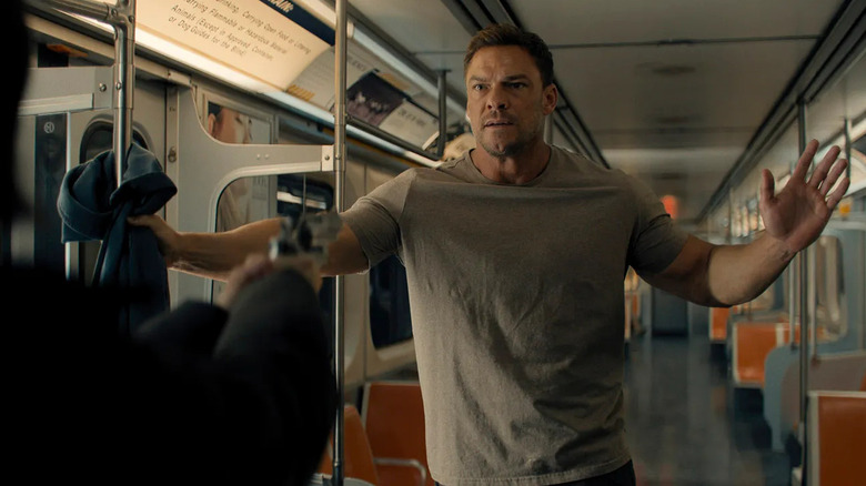 Alan Ritchson as Jack Reacher, held at gunpoint on a subway in Reacher.