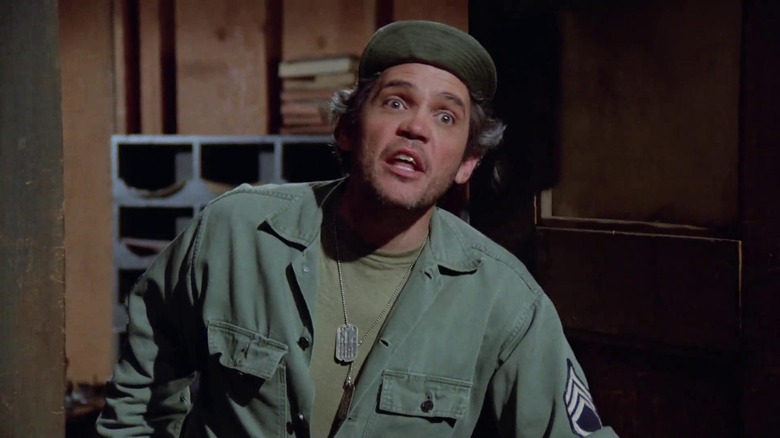 Luther Rizzo (G.W. Bailey) speaks in an office in M*A*S*H