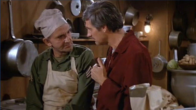 Salvatore Pernelli (Val Bisoglio) speaks with Hawkeye Pierce (Alan Alda) in a kitchen in M*A*S*H