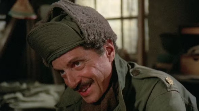 Sidney Freedman (Allan Arbus) sits smiling and wearing a winter hat in M*A*S*H
