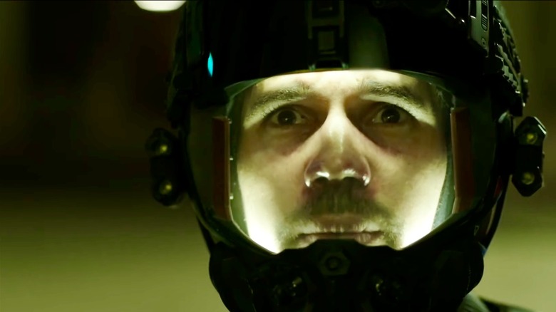 Close up of Jim Holden in an environmental suit helmet, looking on
