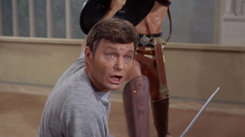 Leonard McCoy (DeForest Kelley) holds up a shield while fighting a gladiator in Star Trek: The Original Series