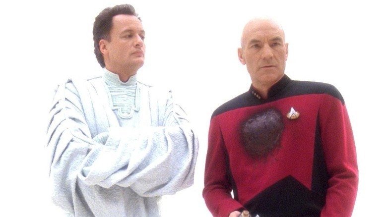 Q (John de Lancie) looks expectantly at a wounded Jean-Luc Picard (Patrick Stewart) in a white void in Star Trek: The Next Generation