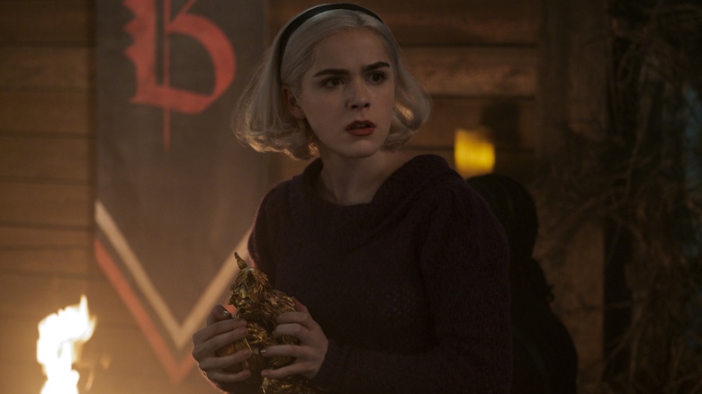 Sabrina (Kiernan Shipka) holding a gold statue on "Chilling Adventures of Sabrina."