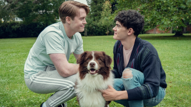Kit Connor as Nick kneeling down next to dog and Joe Locke as Charlie in Heartstopper
