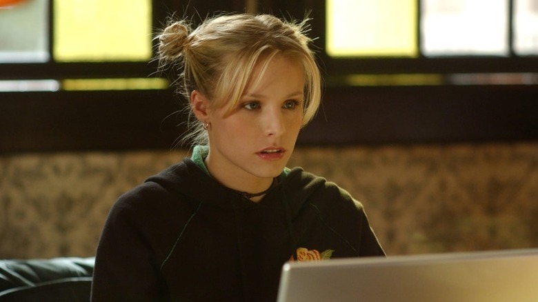 Kristen Bell as Veronica Mars with hair in buns sitting in front of laptop in Veronica Mars