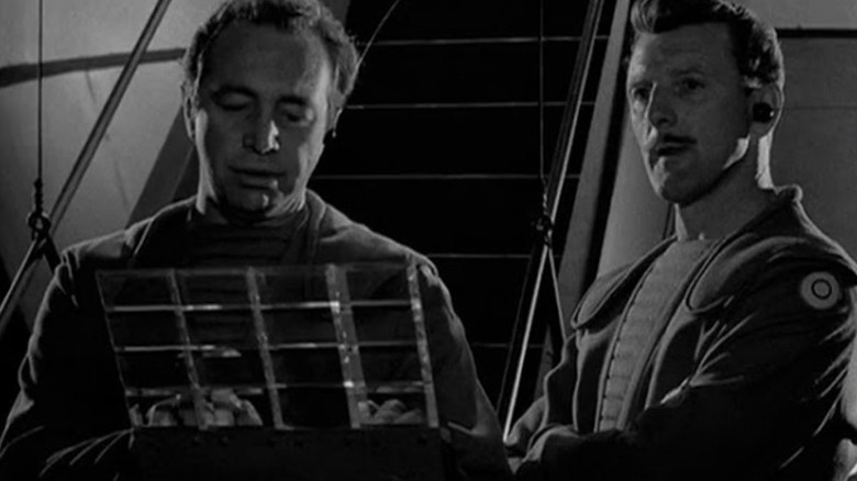 Two humanoid aliens operating machinery