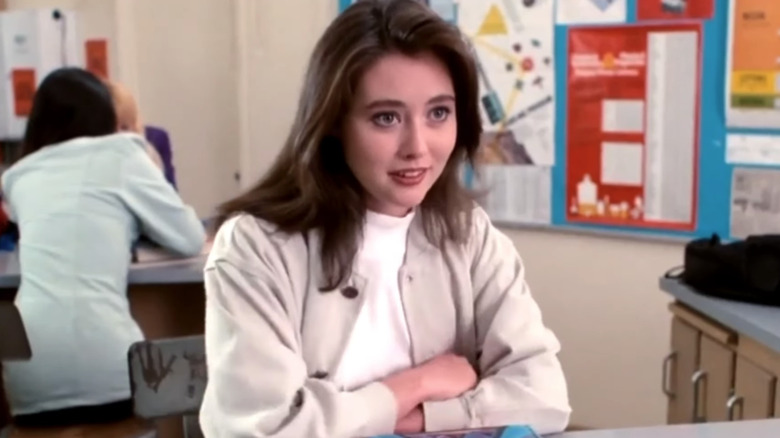 Shannen Doherty as Brenda Walsh leans on a desk in Beverly Hills 90210
