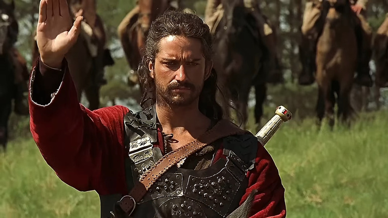 Gerard Butler as Attila the Hun wearing armor and a sword on his back while surrounded by an army in Attila.