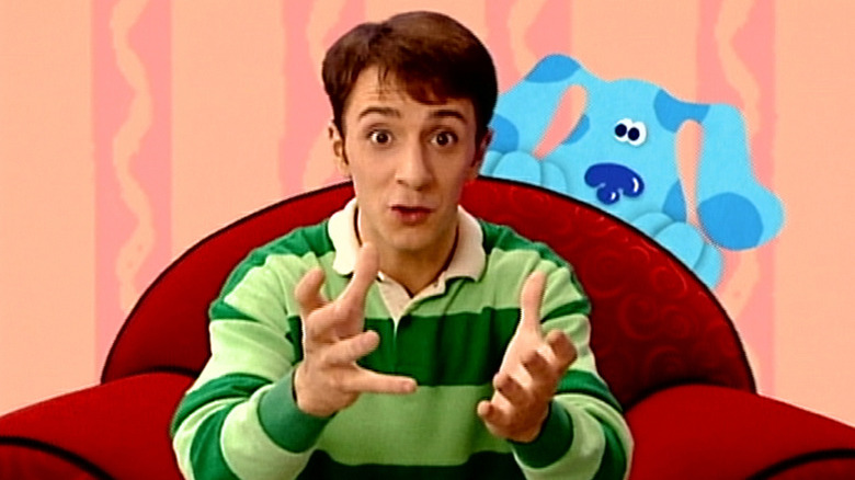Steve Burns sitting in his chair with Blue sneaking up behind him in Blue's Clues