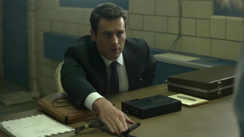 Holden touching a microphone on a desk