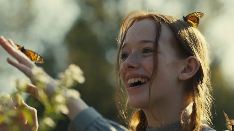 Anne Shirley (Amybeth McNulty) laughs while butterflies land on her in Anne with an E