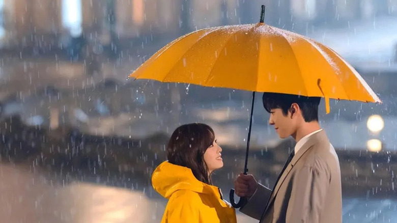 Kang Tae-moo (Ahn Hyo-seop) holds a yellow umbrella over Shin Ha-ri (Kim Se-jeong) in Business Proposal