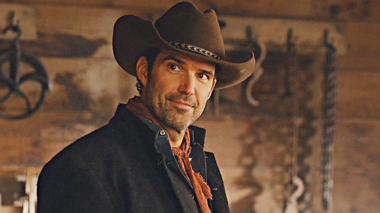 Benjamin Ayres' Tom Moore wearing a brown cowboy hat and smiling on Hope Valley: 1874