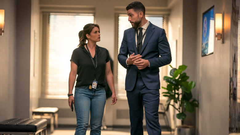 Maggie Bell and Omar Adom Zidan speaking to each other while walking down a hallway