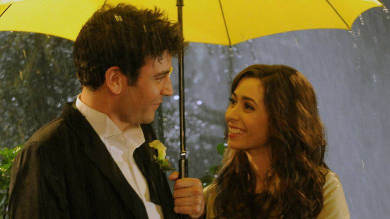 Josh Radnor and Cristin Milioti as Ted and Tracy sharing a yellow umbrella in How I Met Your Mother
