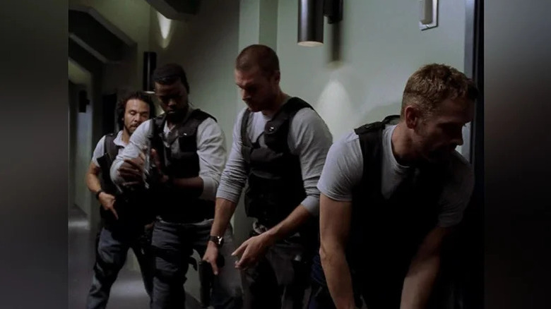 Four special forces soldiers line up in a hallway