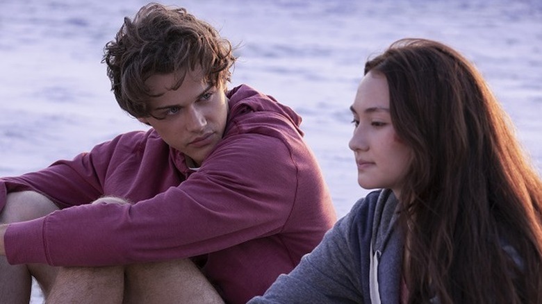 Christopher Briney as Conrad sitting on the beach next to Lola Tung as Belly in The Summer I Turned Pretty