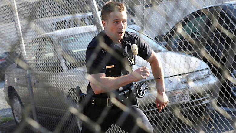 Ben Sherman (Ben McKenzie) runs behind a chain-link fence in Southland