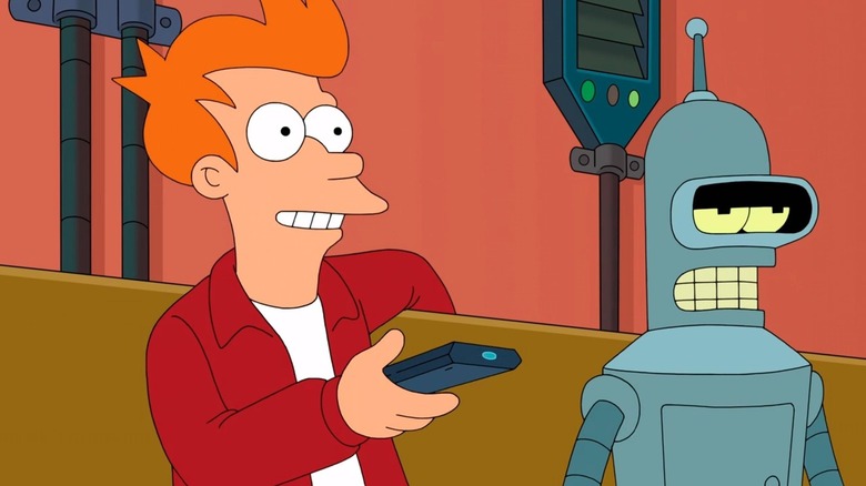 Philip J. Frye (Billy West) smiles holding a remote control while sitting on a couch with Bender (John DiMaggio) in Futurama