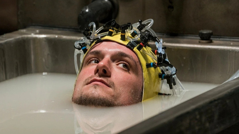 Josh Futturman (Josh Hutcherson) sits in a steel tub with dirty water up to his head while wearing a strange headpiece in Future Man